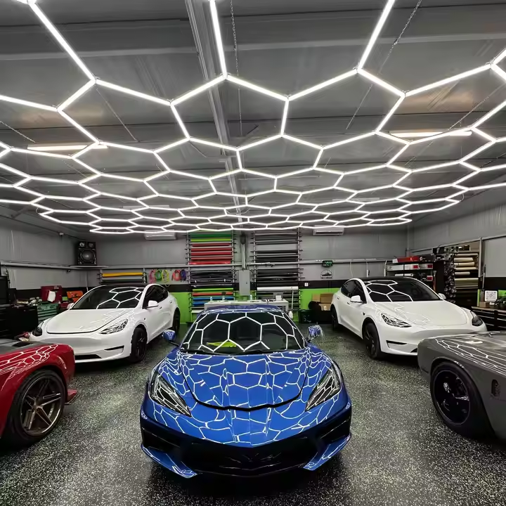 Hexagon LED lights installed across a home workshop ceiling above tool chests, storage cabinets and parked vehicles