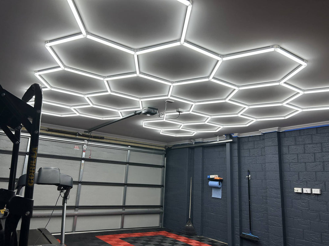 Hexagon LED grid over a garage workout space with a treadmill by the sectional door