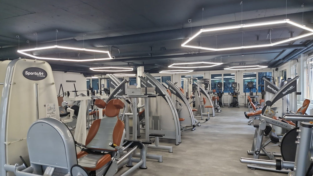 Row of large hexagon light frames hung over the machine aisle of a commercial gym