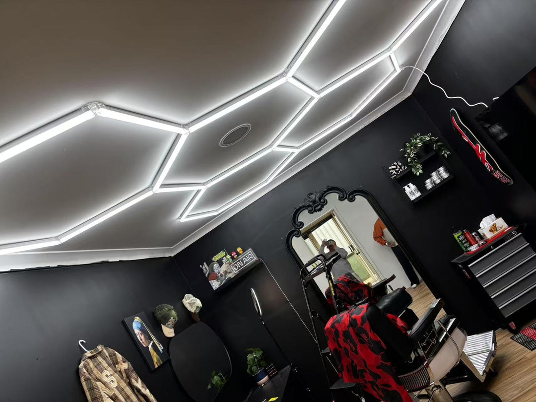 Barbershop lighting with a hexagon LED grid across the ceiling of a black-walled barbershop