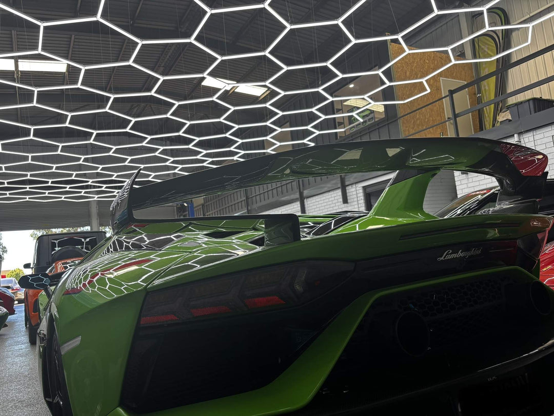 Hexagon LED grid covering a garage ceiling above a green supercar