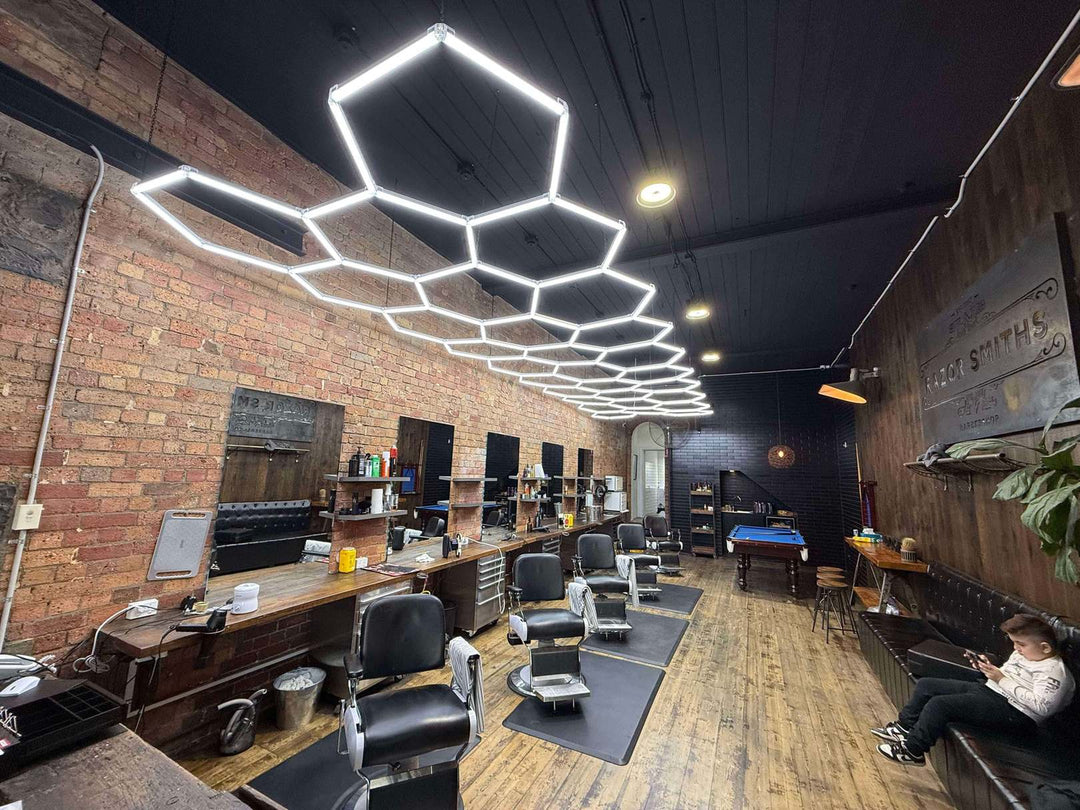Red brick barber shop with a long hexagon LED grid on a black ceiling above a row of barber chairs
