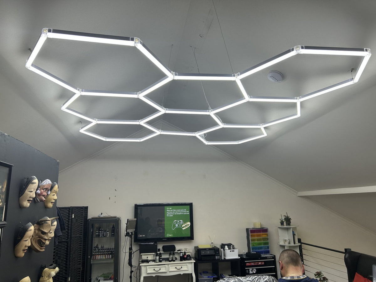 Hexagon light grid hung level on suspension wires under the sloped white ceiling of a small studio