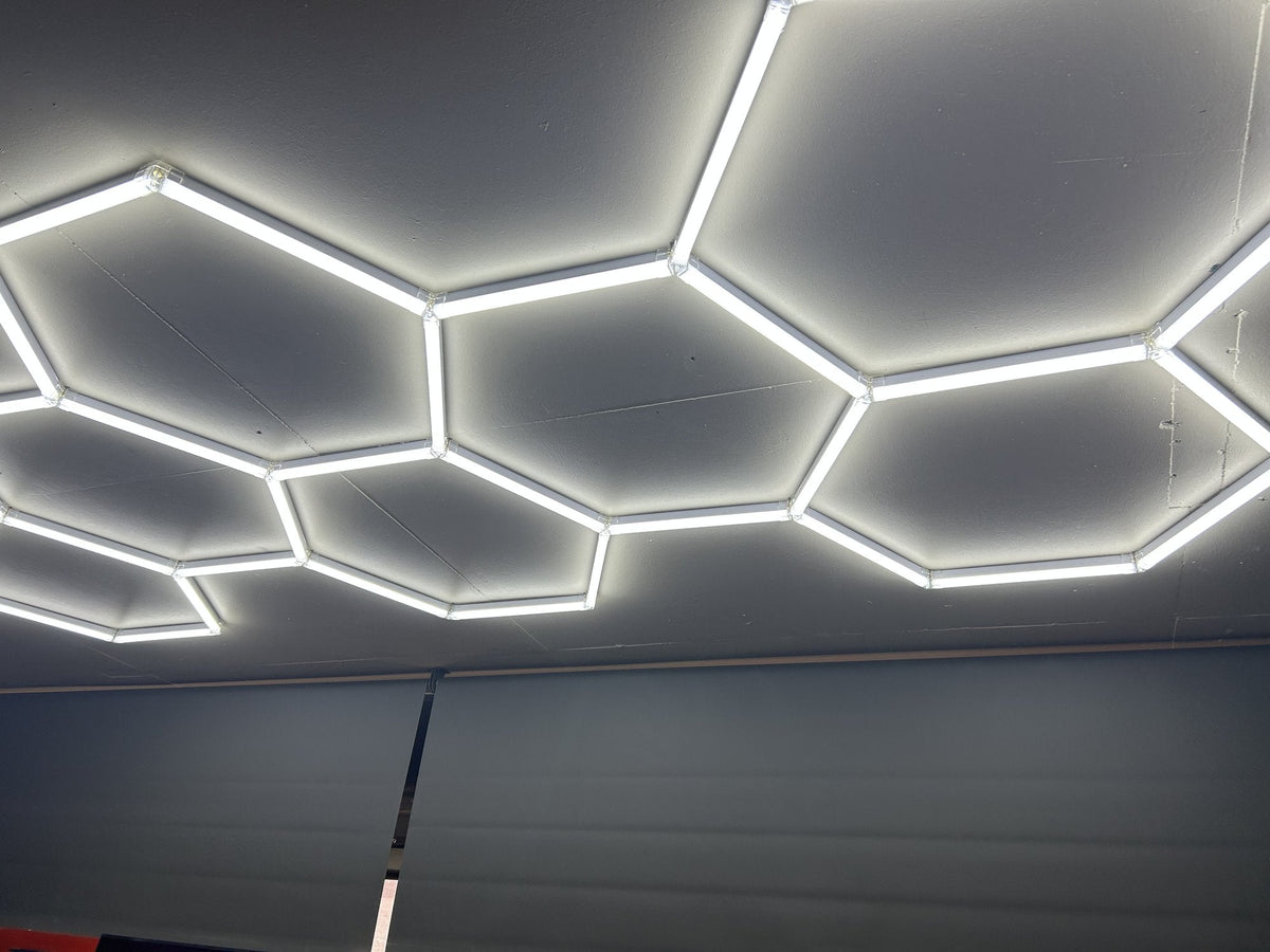 Large hexagon LED light frames on a gray garage ceiling above a sectional garage door