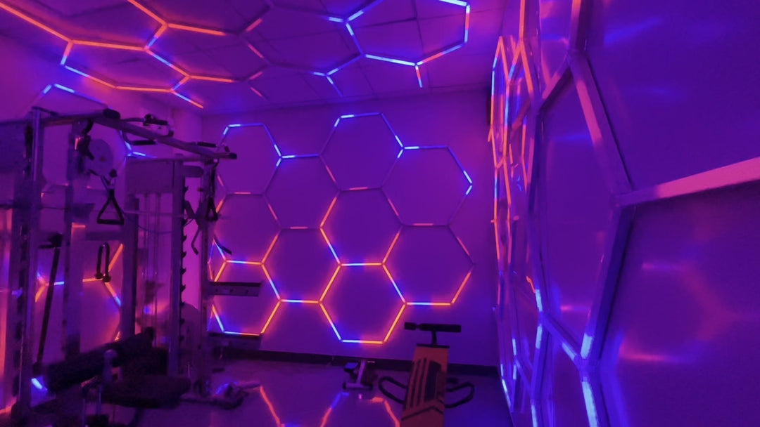 Gym with RGB hexagon lights on the walls and ceiling glowing purple and pink around a power rack