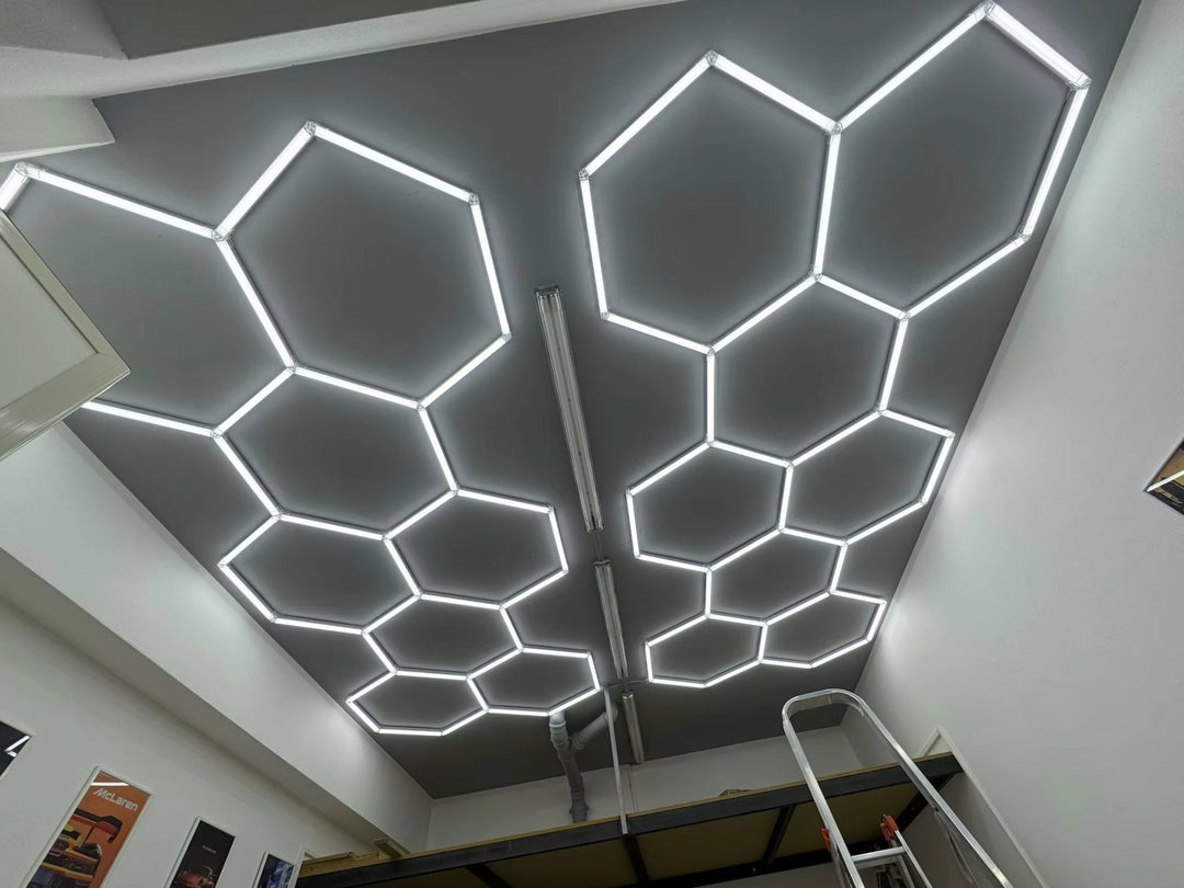 Two hexagon light grids glowing on a gray ceiling in a bright white room